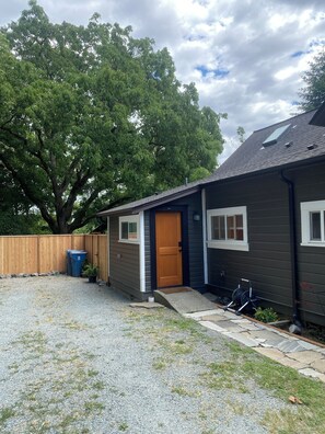 A residential house with a wooden door, a gravel driveway, and a large tree in the background. - Downtown Snohomish - River Views - Walk to Town (Snohomish)