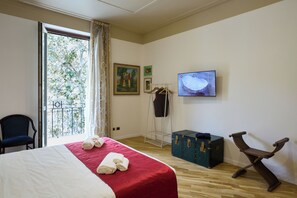 Ein Hotelzimmer mit Bett, Fernseher, Balkon, Stuhl und Schrank.