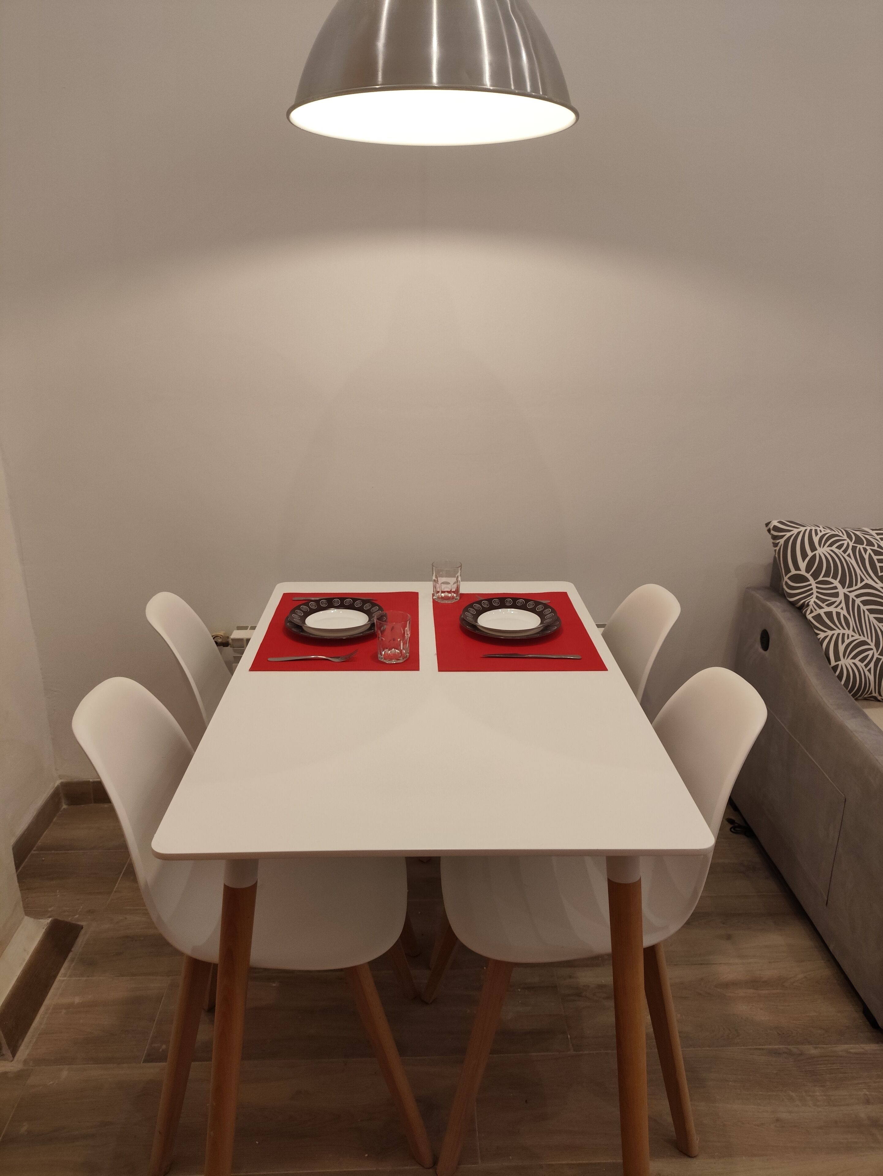 A dining table with two plates, a glass, and a spoon.