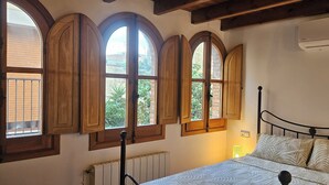 Un dormitorio con cama, marcos de ventana de madera y un radiador.