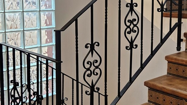 Una escalera con barandillas negras ornamentadas y escalones de madera.