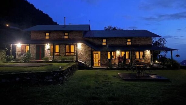 Ein zweistöckiges Steinhaus mit zahlreichen Fenstern und einer überdachten Terrasse.