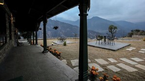 Un'area esterna riparata, con pavimento in pietra, un tavolo e sedie, e vista sulle montagne sullo sfondo.