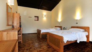Quarto com duas camas de madeira, uma escrivaninha de madeira e um banco.