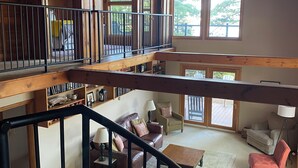 Un loft espacioso con interior de madera, una escalera y un balcón con vistas a una terraza.