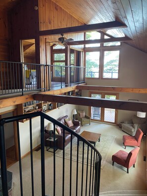 A spacious loft with a wooden interior, a staircase, and a balcony overlooking a deck. - Lakefront 4-Bedroom Home on Lake Champlain with Stunning Views (Isle La Motte)