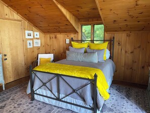 Een kamer met houten lambrisering, een bed, een stoel en een deur.