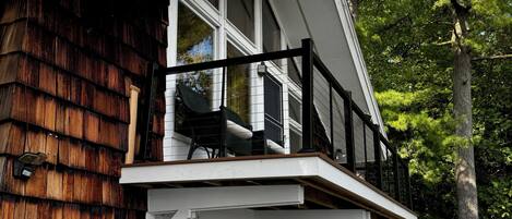 Et toetagers hus med balkon, store vinduer og en træterrasse.