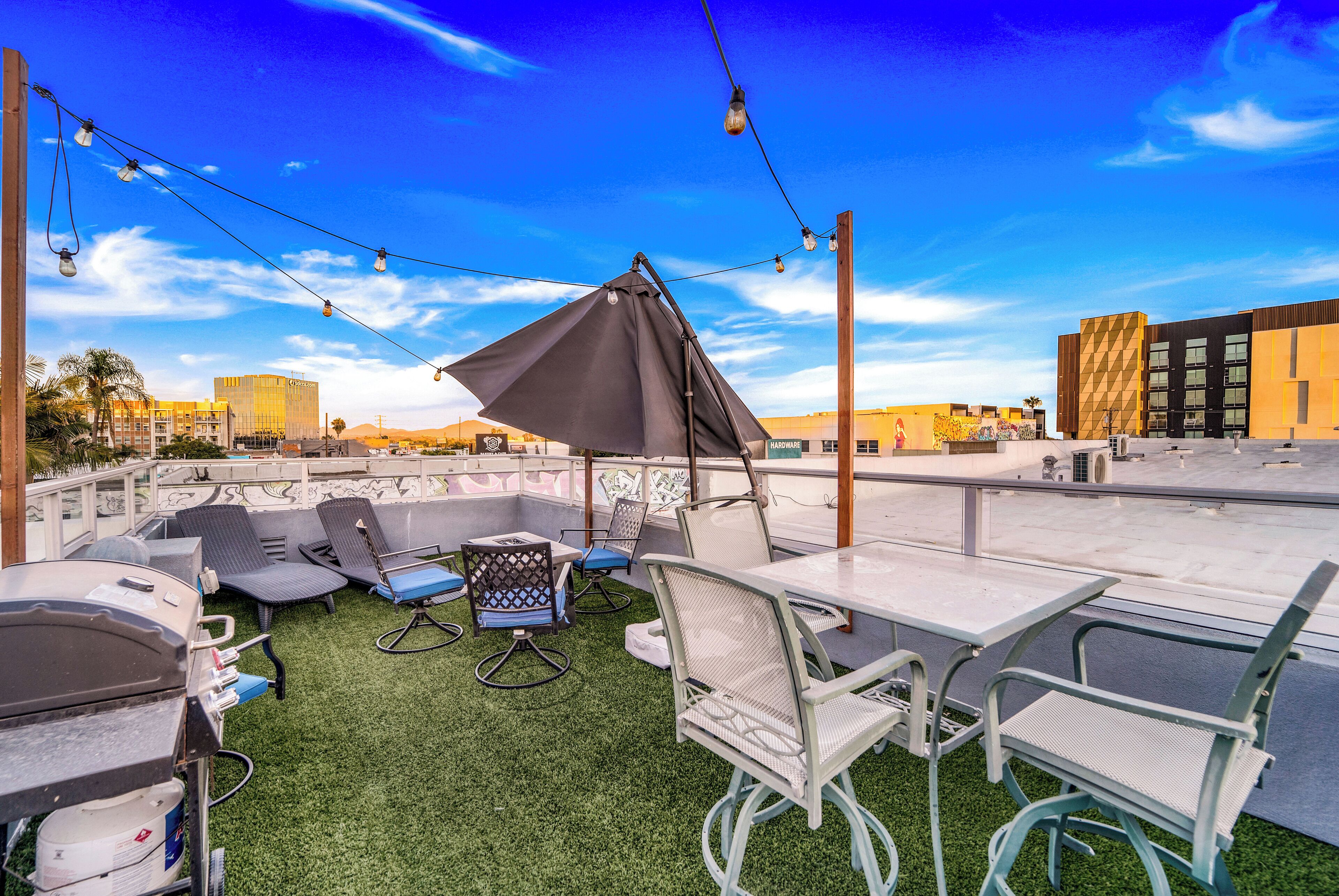 A rooftop terrace with outdoor seating, a grill, and a view of the city skyline.