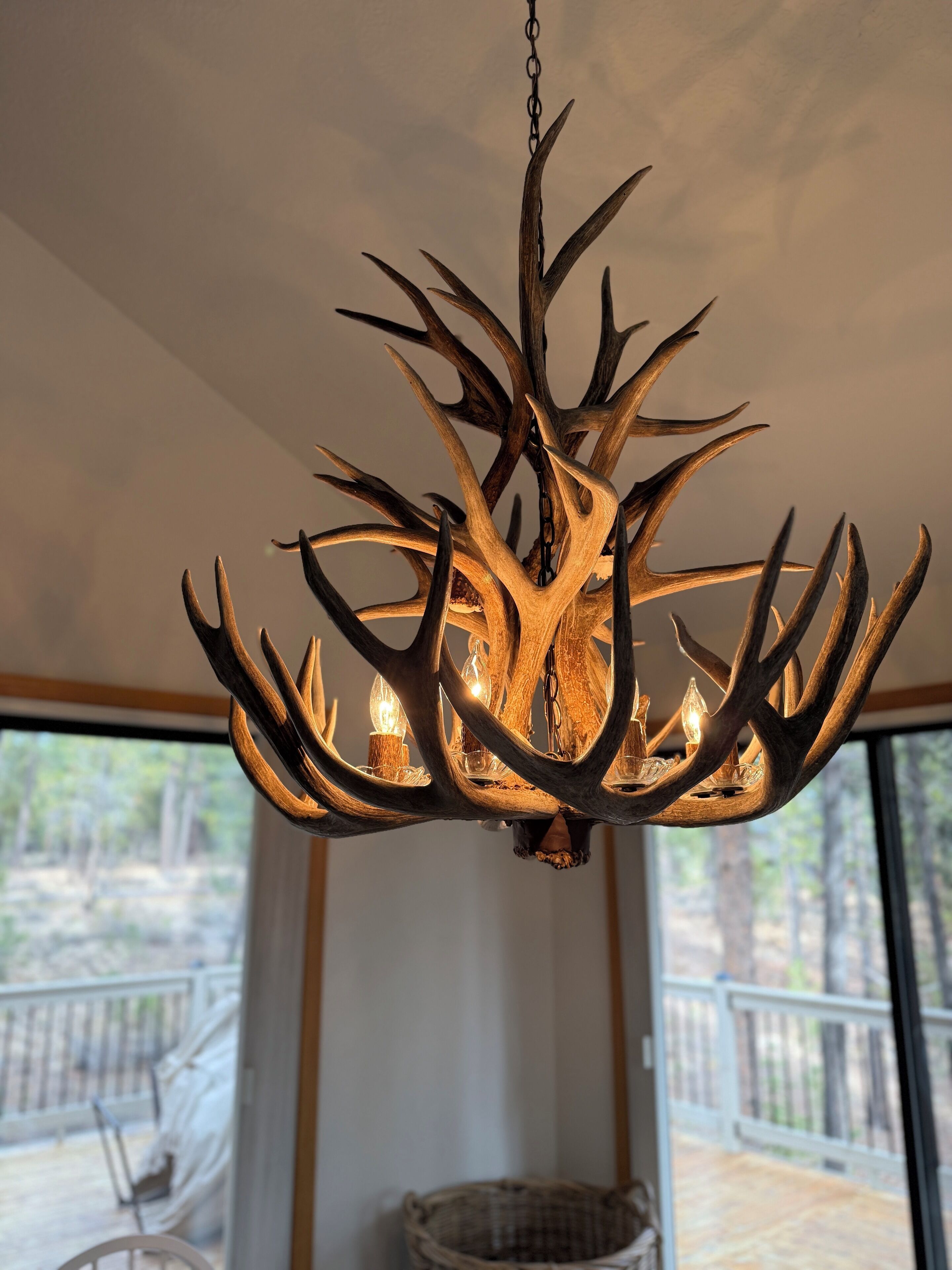 A chandelier with antler-shaped metal branches and candles.