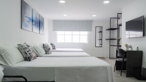 Une chambre d’hôtel moderne équipée de deux lits, d’une grande fenêtre, d’un téléviseur à écran plat et d’un bureau avec une chaise.