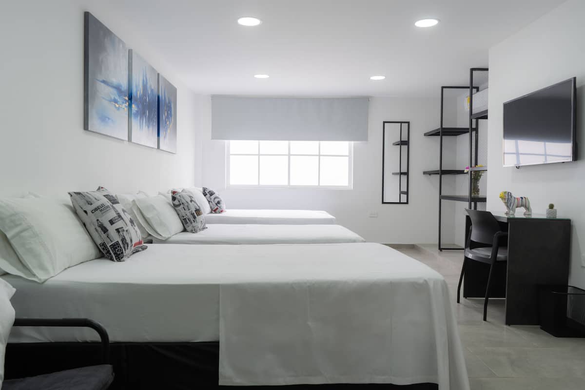 A modern hotel room with two beds, a large window, a flat-screen TV, and a desk with a chair.