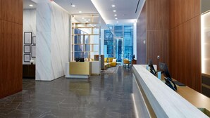 A modern reception area with a marble floor, wooden paneling, and a seating area with yellow chairs. -  Time Square Hilton Studio Premier available for New Year's Eve in New York City (New York)