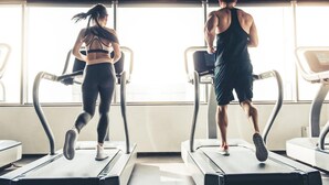 Two people running on treadmills in a gym with large windows. -  Time Square Hilton Studio Premier available for New Year's Eve in New York City (New York)