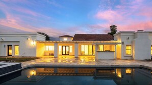 Et moderne hus med swimmingpool, store vinduer og en patio.