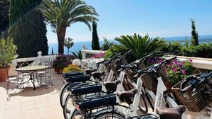 A terrace with multiple bicycles, a table, and chairs, overlooking a scenic view with cypress trees and a clear sky. - Sumptuous Mediterranean villa in Cannes (Cannes)