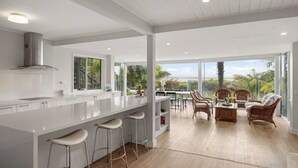 Una cocina moderna con una isla grande, taburetes de bar y un comedor con muebles de mimbre.