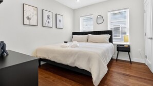 Een moderne slaapkamer met een bed, nachtkastjes en kunstwerken aan de muur.