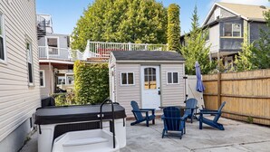 Een achtertuin met een jacuzzi, terrasmeubels en een kleine schuur.