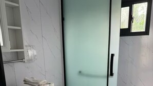 A bathroom with a toilet, a sink with a mirror, and a shower area. - TH2-Enjoy the serenity of the lake in the comfort of this 2 bedroom tiny home. (Bridgeport)