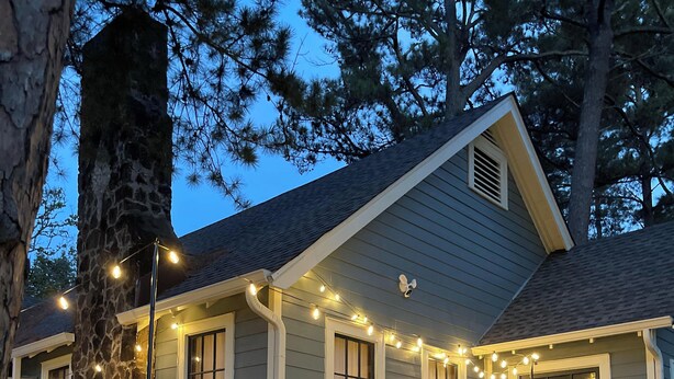Ein Haus mit einem Steinkamin, einer roter Tür und Lichterketten an der Veranda.