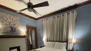 Ein Schlafzimmer mit Bett, Deckenventilator, Kamin und Teppich.