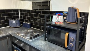 A kitchen with a gas stove, a microwave, a toaster, and a coffee maker.