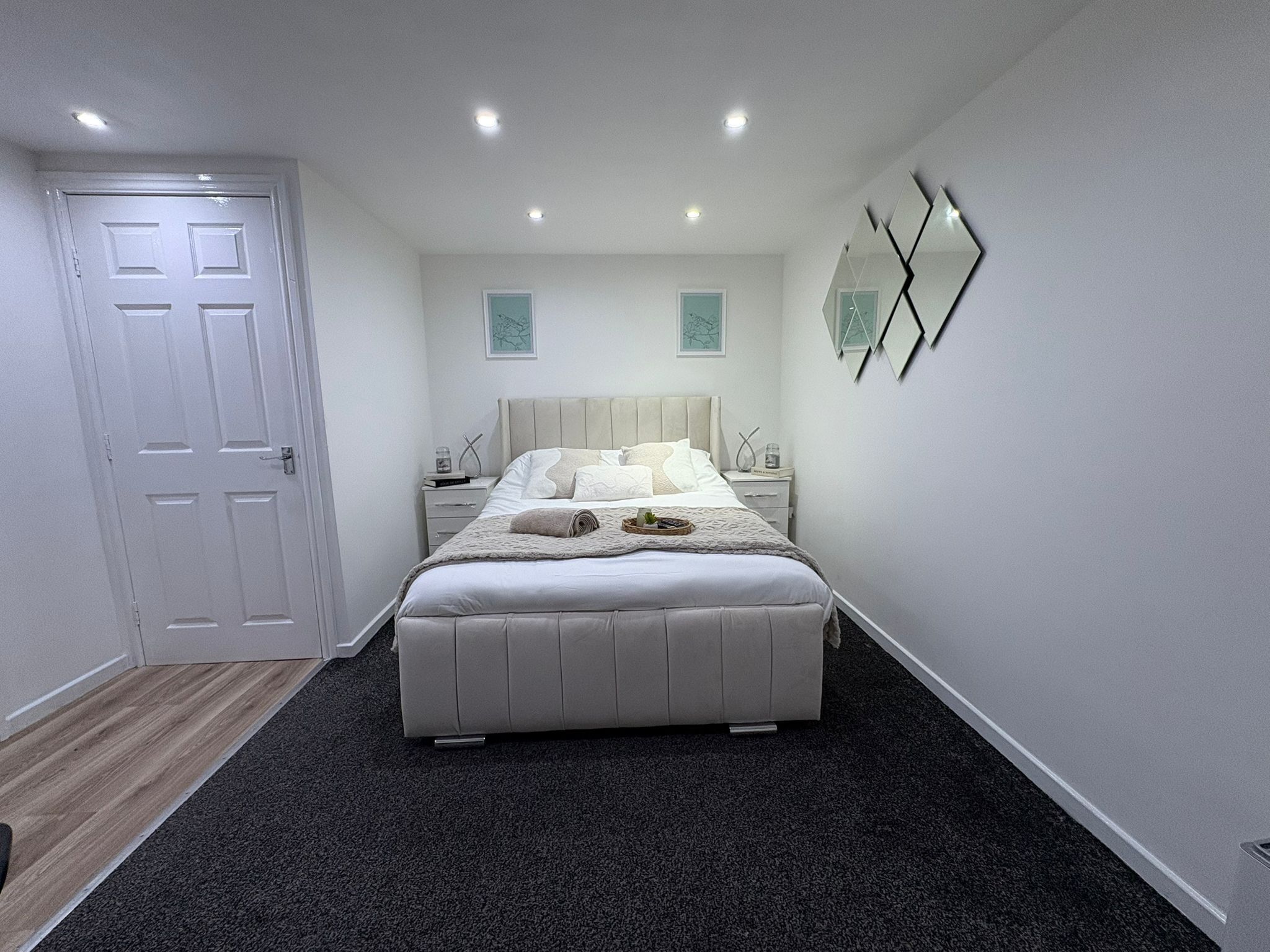 Een moderne slaapkamer met een groot bed, een nachtkastje en een deur.