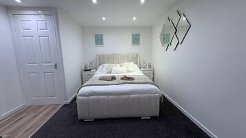 Een moderne slaapkamer met een groot bed, een nachtkastje en een deur.