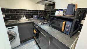 A compact kitchen with a washing machine, a microwave, and a toaster.