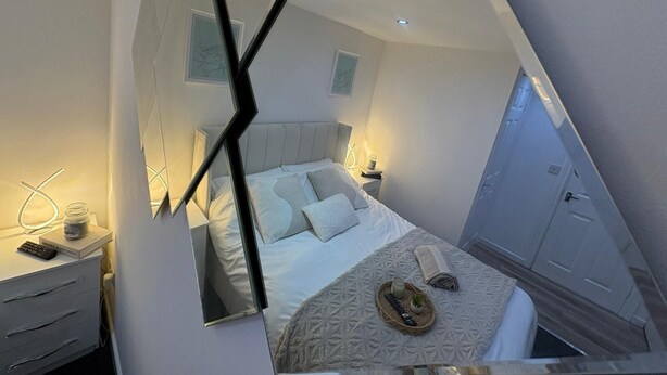 A modern bedroom with a bed, bedside tables, and a wardrobe.