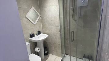 Een douche, handdoeken, zeep, toiletpapier