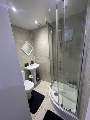 Een douche, handdoeken, zeep, toiletpapier