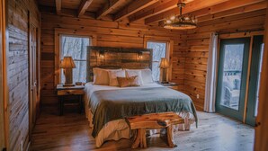 Ein Schlafzimmer in einer Blockhütte mit einem hölzernen Bett, Nachttischen und einer Bank.