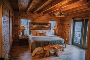 Une chambre située dans une cabane en rondins, avec un lit en bois, des tables de chevet et un banc.