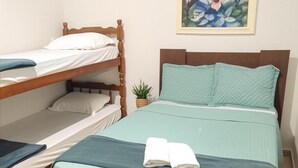 Une chambre avec un lit superposé, un lit simple et une petite plante en pot.