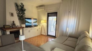 Een woonkamer met een bank, een salontafel, een televisie, een lamp en een plant.