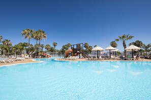 A swimming pool with lounge chairs and palm trees.