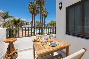A wooden table with breakfast items, a view of a pool, and palm trees.