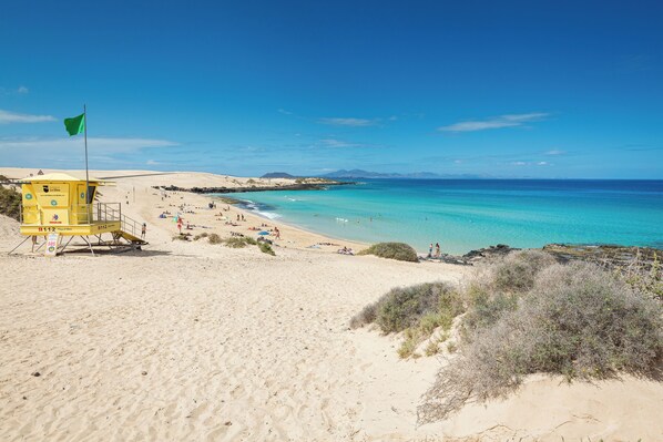A beach with a lifeguard tower, clear blue sky, and calm sea.