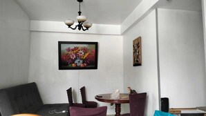 A dining area with a round table, chairs, a chandelier, and two framed artworks on the walls. - Apartment in north downtown Quito, close to all parks and shopping centers. (Quito)