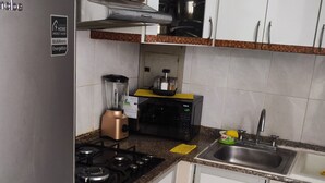 A compact kitchen with a refrigerator, stove, microwave, and a small sink. - Apartment in north downtown Quito, close to all parks and shopping centers. (Quito)