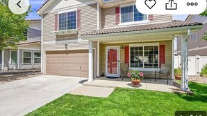 Ein zweistöckiges Haus mit Garage, überdachter Veranda und gepflegtem Rasen.