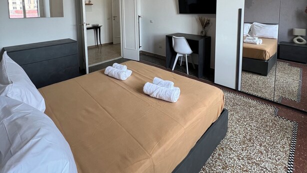 Une chambre d’hôtel avec un lit, un bureau, une télévision et un miroir.