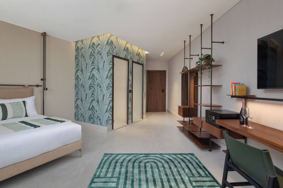 Een moderne hotelkamer met een bed, een bureau, een stoel, een televisie en een boekenkast.