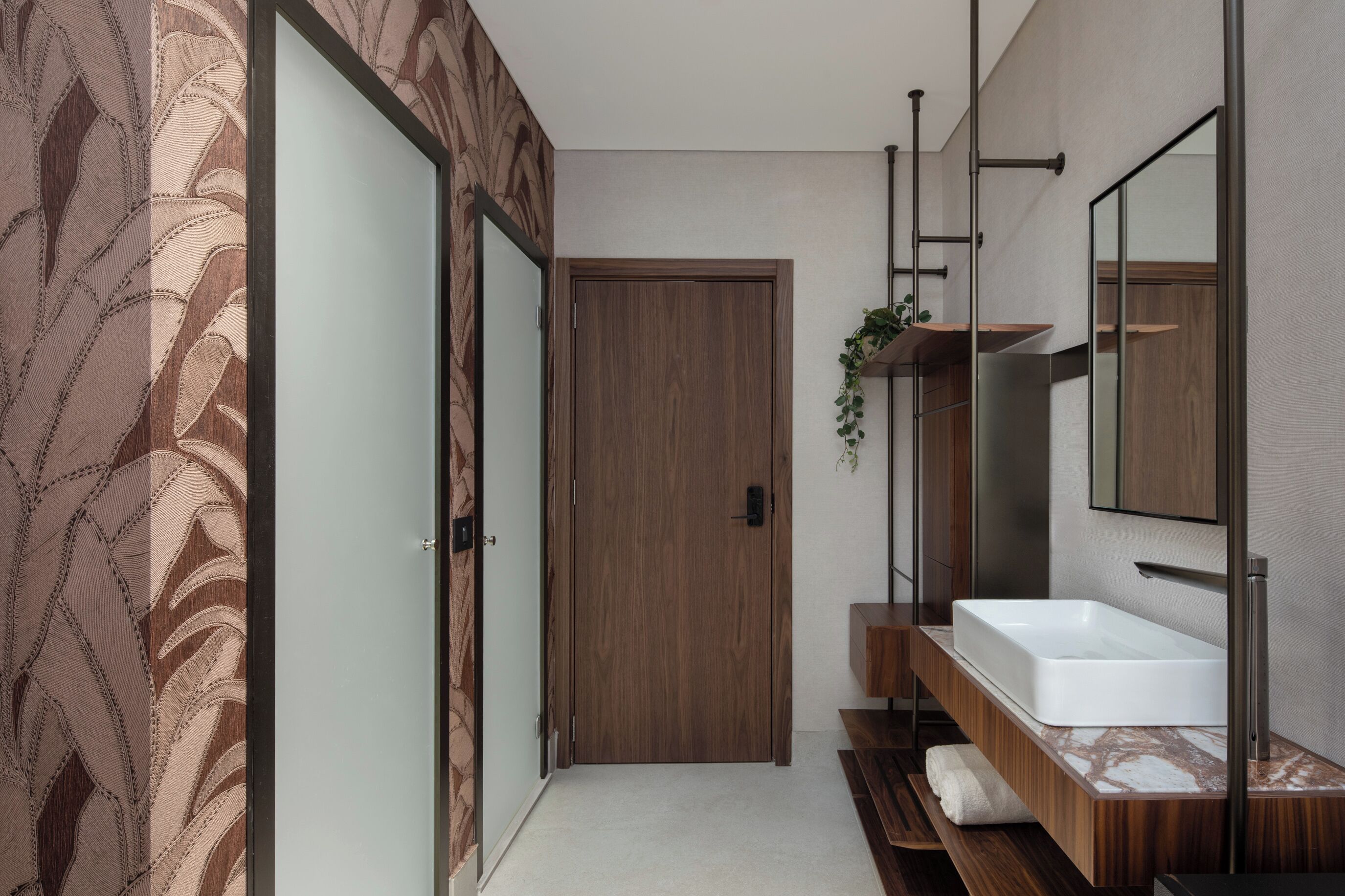 A modern bathroom with a wooden door, a large mirror, and a white sink.