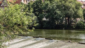A historic building with a clock tower, surrounded by trees and a river. - Belsers Hotel (Nuertingen)