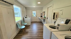 A laundry room with a washing machine, dryer, and a small seating area with chairs. - 30-A Getaway near Seaside, FL --Great for Snowbirds, couples, or small families (Santa Rosa Beach)