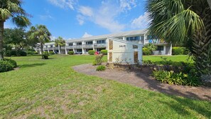 A hotel with a well-maintained lawn, a small utility shed, and a multi-story building with balconies. - 30-A Getaway near Seaside, FL --Great for Snowbirds, couples, or small families (Santa Rosa Beach)
