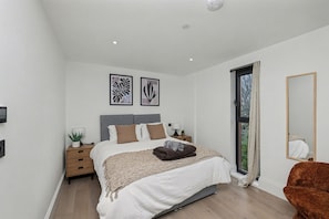 Quarto moderno com cama, mesas de cabeceira, espelho e obras de arte na parede.
